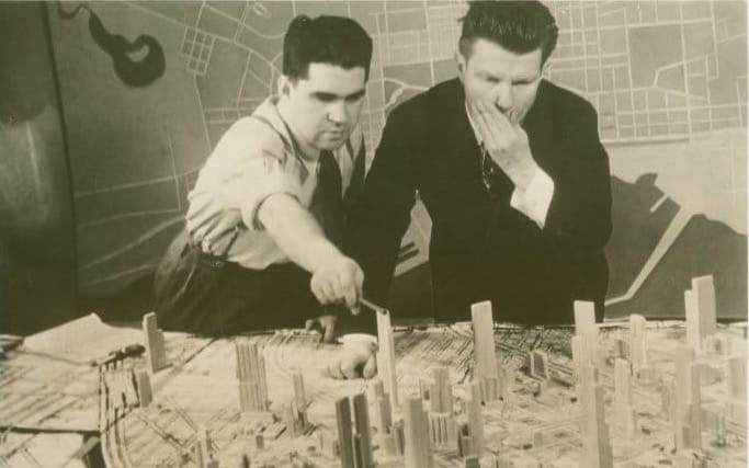 Norman Bel Geddes with man looking at model of futuristic city